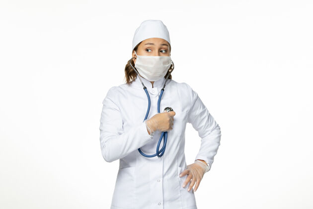 工作正面图白墙上穿着白色医疗服和口罩的女医生潘多米病毒病病毒医生疾病