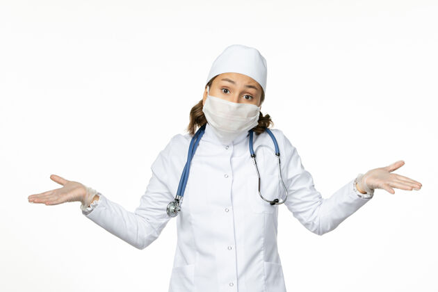 冠状病毒正面图女医生穿着白色医疗服 戴着口罩 因白墙上有冠状病毒大流行 病毒病隔离冠状病毒到期疾病视图