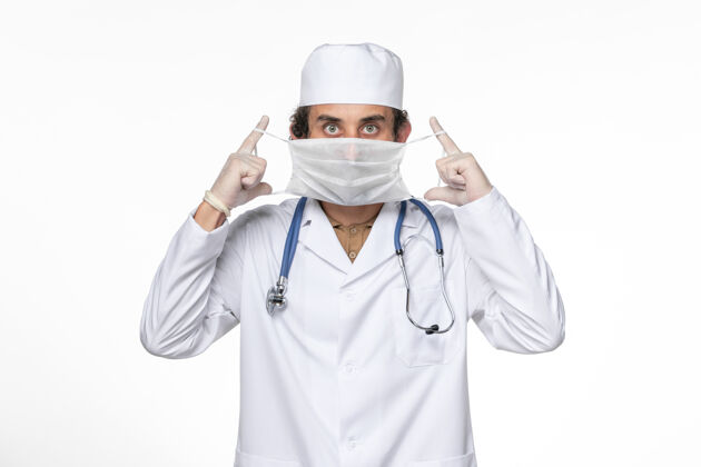 穿戴正面图男医生穿着医疗服戴着口罩在白墙上对抗冠状病毒大流行医学医务人员大流行护目镜