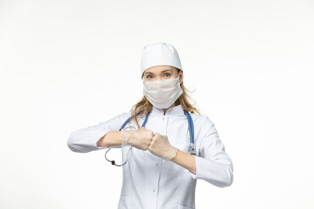 正面正面图女医生穿着医疗服 带着无菌口罩 由于白色墙壁上的冠状病毒大流行健康病毒人套装冠状病毒