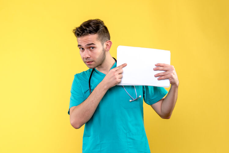 健康年轻男医生的正面图 浅黄色的墙上有文件持有病毒人