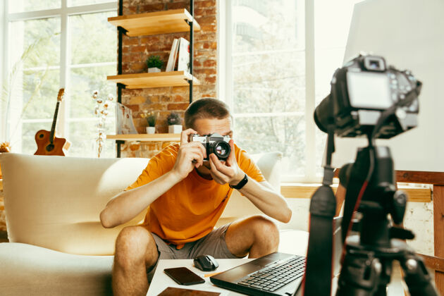 广播年轻的白种男性博主用专业的摄像设备在家里录像点评男性流技术