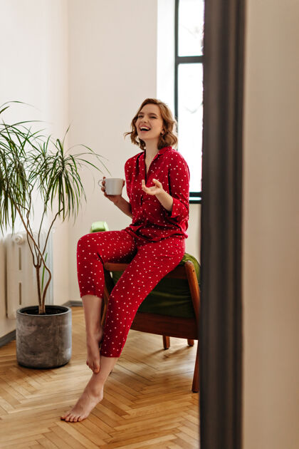 休闲穿着睡衣的兴奋的赤脚女人拿着一杯咖啡在家里喝茶微笑的快乐女人的全景花睡衣清醒