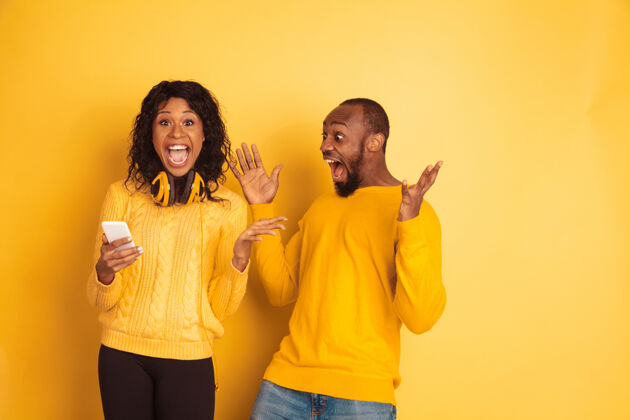 化妆年轻动情的非裔美国人男女在黄色的空间里穿着鲜艳的休闲服美丽的情侣情感选择广告