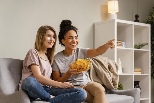 休闲坐在沙发上看电视吃薯片的女人沙发房子薯条