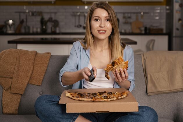 室内女人一边看电视一边吃比萨饼电视遥控器房子披萨