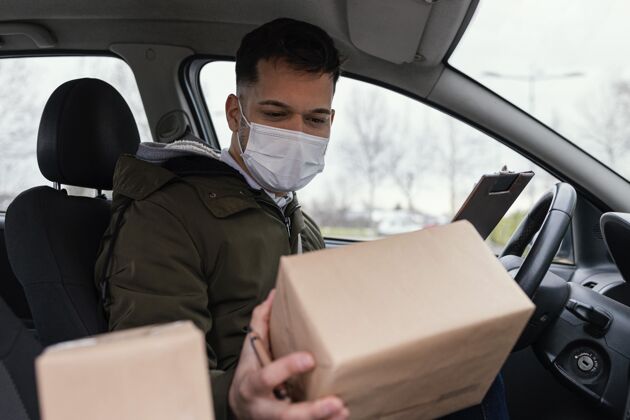 口罩带着面具和包裹的男性送货员人包装送货服务