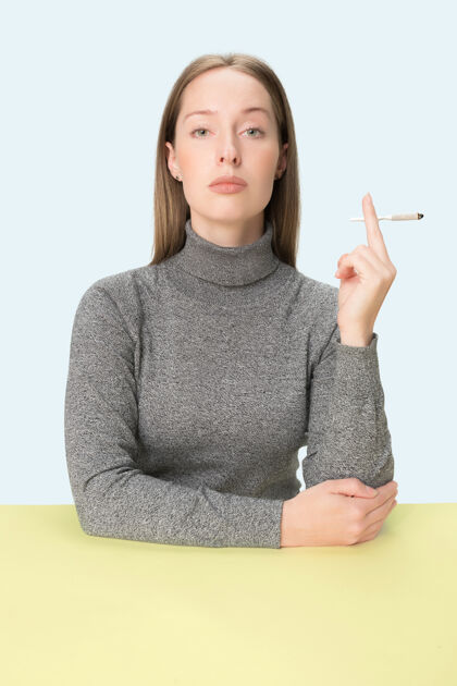 坐着坐在桌子旁抽烟的年轻女子严重香烟白天