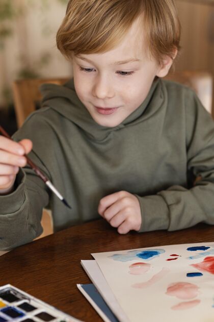 艺术家特写可爱的孩子看刷子垂直内部绘画