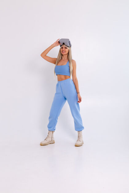 女性摄影棚照片中一个年轻迷人的女子穿着温暖的蓝色时尚西装 戴着虚拟现实眼镜在白色的小玩意现实科技