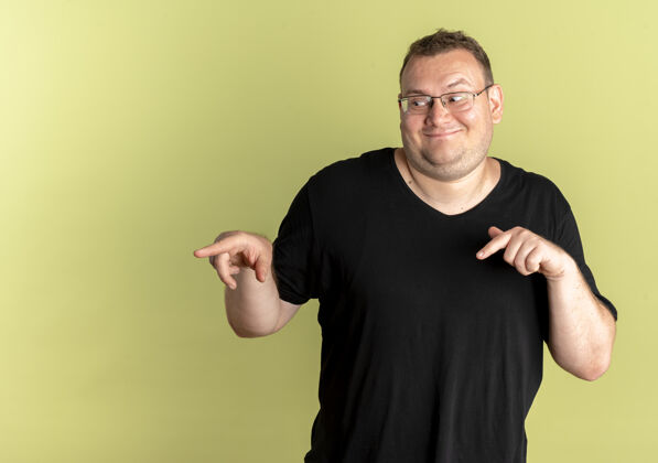 目录戴眼镜的胖男人穿着黑色t恤 食指指向站在轻质墙上的一边支架手指请戴