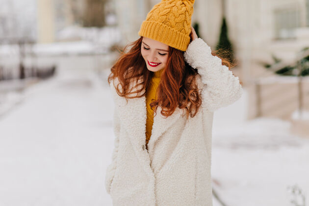 时尚浪漫的姜女在户外拍照时俯视优雅的白种女人在冬天在城市里漫步深色头发一月街头风格
