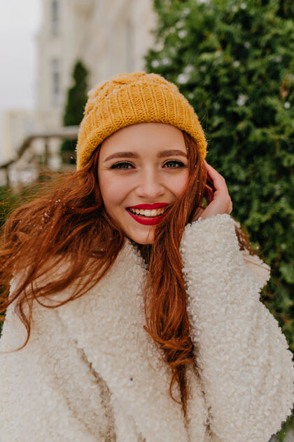 时尚兴奋的红发女人戴着针织帽子在冬天摆姿势浪漫的姜黄色女人穿着外套在户外微笑可爱帽子笑