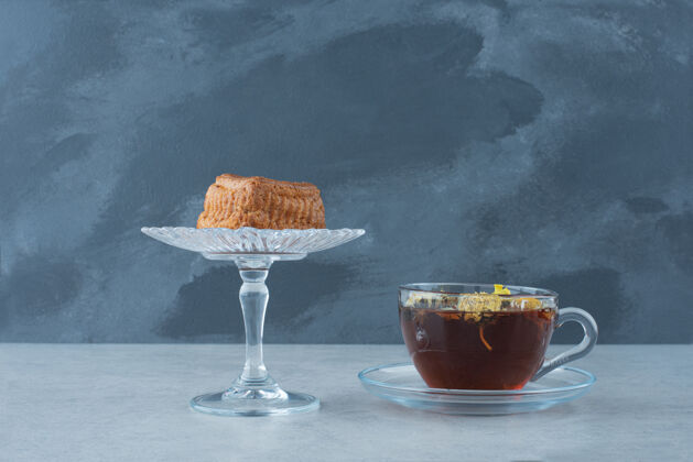 热饮料杯形蛋糕放在玻璃盘上 深色背景上放着热花草茶高质量的照片饮料饼干杯子