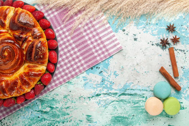 鱼俯瞰美味的派红色草莓和麦卡龙在蓝色的表面饼干美食派