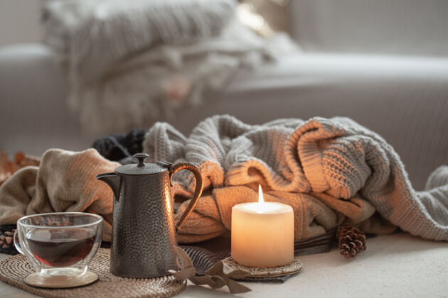 茶一支发光的蜡烛 一杯茶和一个茶壶 在房间里温暖的毛衣的衬托下线程静物杯子
