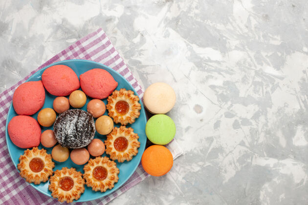 柑橘俯瞰美味的蛋糕和饼干和麦卡龙在白色的表面食品甜食马卡龙