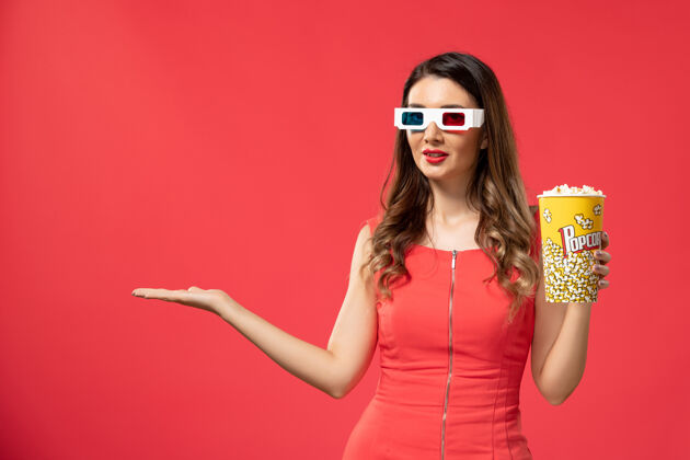 电影正面图红色表面上戴着d墨镜拿着爆米花的年轻女性太阳镜头发爆米花