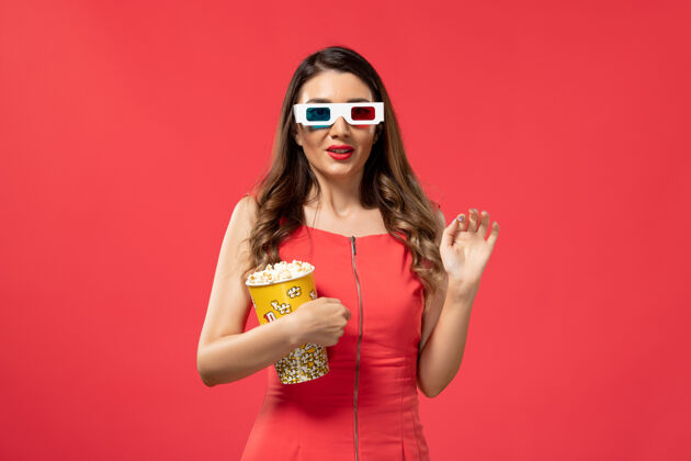 持有正面图年轻女性手持爆米花包戴着d墨镜在红色表面性感爆米花电影