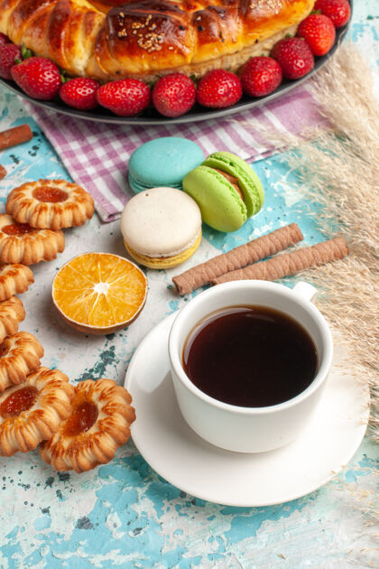 营养素正面是美味的甜馅饼 蓝色表面有红色草莓饼干和茶新鲜的美味咖啡