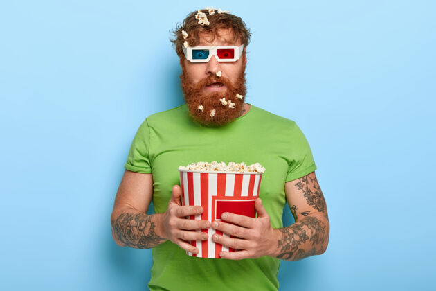 惊喜迷惑不解的红发男子透过电影院的眼镜盯着镜头眼镜人水桶
