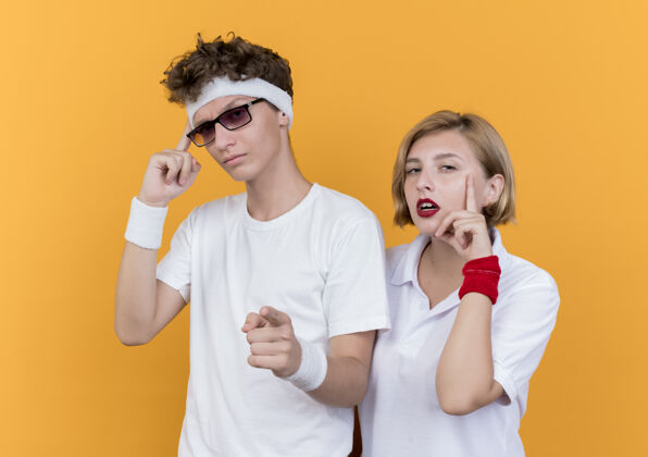 男人一对年轻的运动情侣手指着太阳穴专注于一项艰巨的任务站在橙色的墙上任务女人运动
