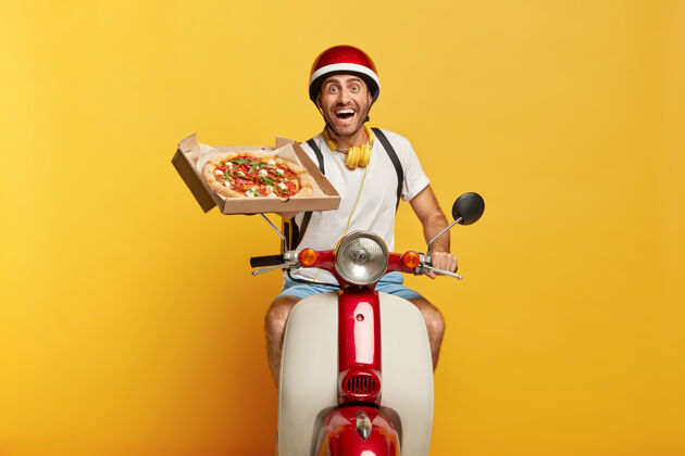 工人快乐勤劳英俊的男司机骑着红色头盔的摩托送比萨饼欢呼家伙美味