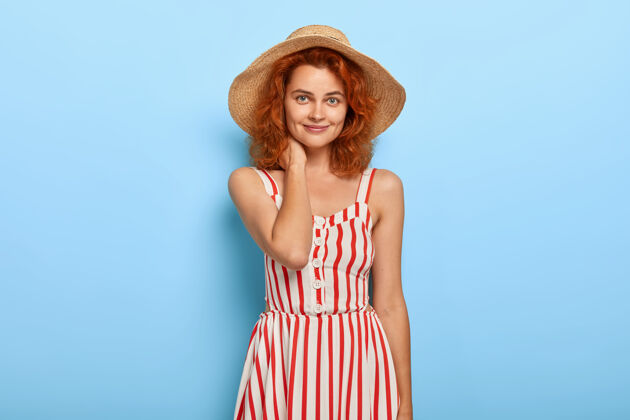 女性姜黄色头发的可爱年轻女士的肖像 穿着夏装 戴着草帽姿势欢呼条纹