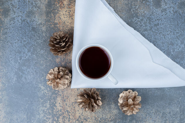 桌布一杯热茶和松果放在大理石桌上高质量的照片液体饮料松果