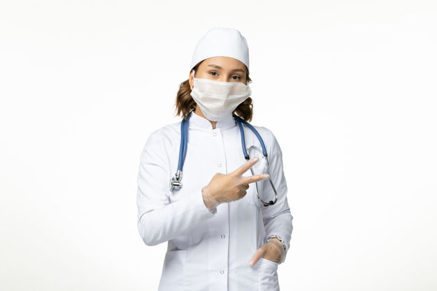 到期正面图年轻女医生戴防护无菌口罩因冠状病毒在灯桌上医生办公桌冠状病毒