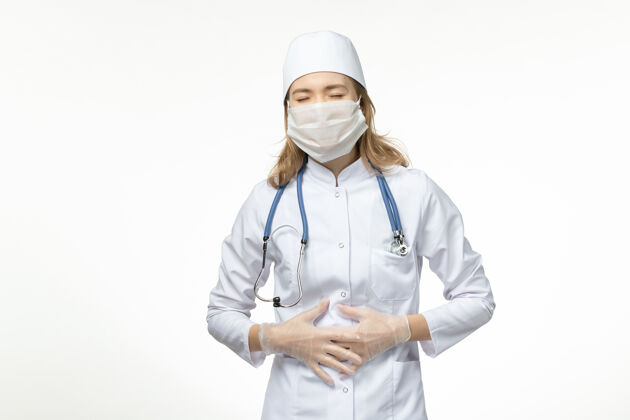 疾病正面图年轻的女医生穿着医疗服 戴着防护面罩 由于冠状病毒在浅白色的表面病毒冠状病毒女性
