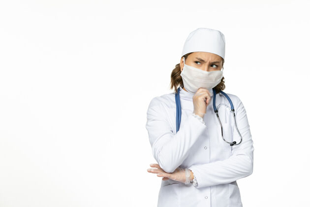 套装正面图年轻的女医生穿着白色的医疗服 戴着口罩 因为白色的表面上有冠状病毒思维疾病冠状病毒正面