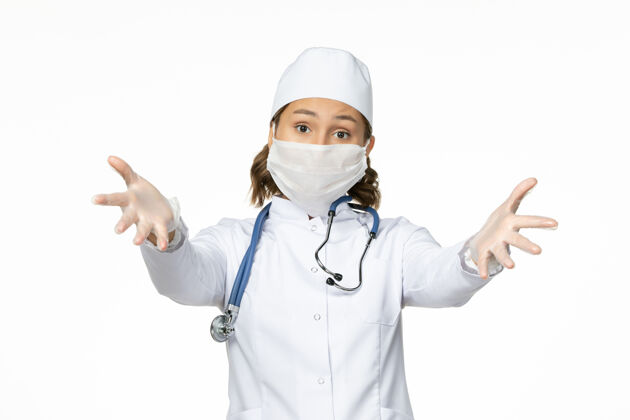 口罩正面图年轻女医生戴着无菌口罩和手套由于白色表面有冠状病毒女性到期手套