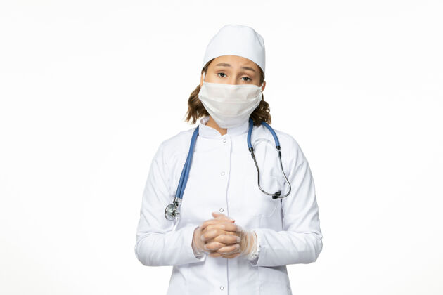 疾病正面图年轻女医生戴着无菌口罩和手套 白色办公桌上有冠状病毒女性大流行专业人员