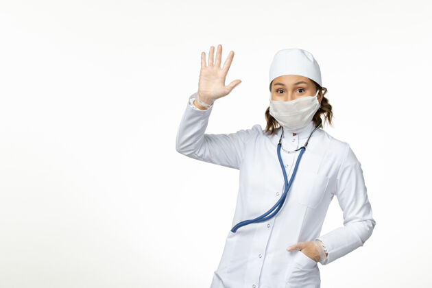 防护正面图年轻的女医生戴着无菌防护口罩 因为冠状病毒把她的手放在白色的桌子上疾病病毒展示