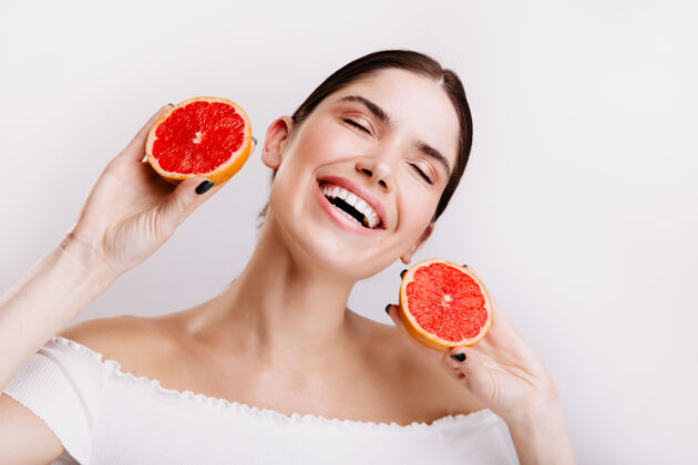 护理充满活力的感性女孩笑着摆姿势 手里拿着红色的柑橘类水果年轻活跃橘子