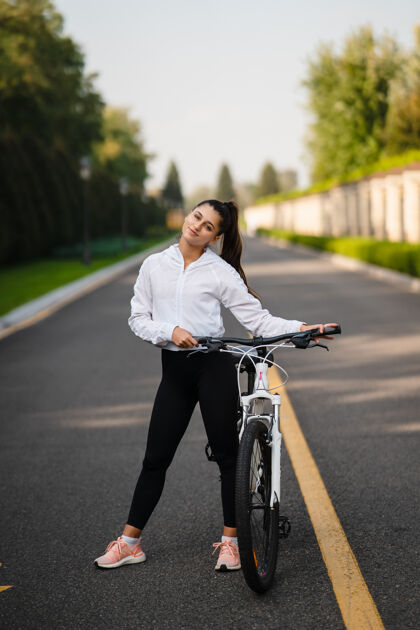 自行车美丽的女孩在白色自行车前摆姿势在大自然中漫步自然女人女人