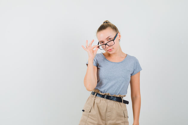 专业年轻女性翻过眼镜 穿着t恤 裤子 看起来很懂事 前视图年轻敏感女人