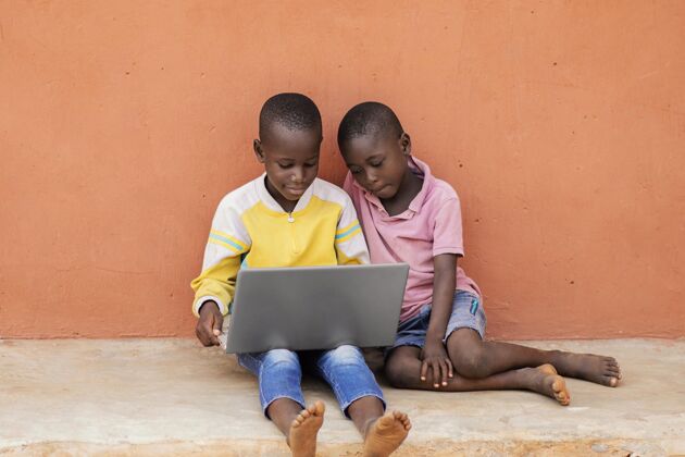 肖像全镜头的非洲孩子用笔记本电脑第三世界水平农村