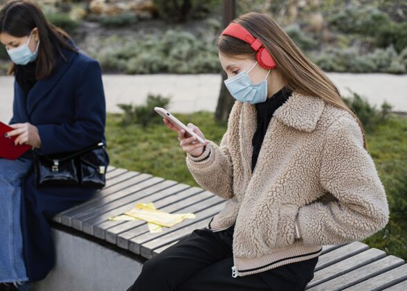社会距离坐在远处戴着面具的人设备耳机冠状病毒