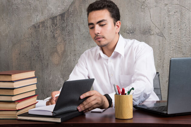 笔记本电脑年轻员工看着笔记本 坐在办公桌前高质量的照片办公室书人