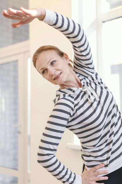 成人中等身材的女人在室内伸展高级锻炼女子