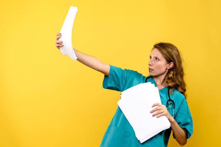 运动装正面图年轻女医生拿着文件放在黄色的空间里医院情绪成人