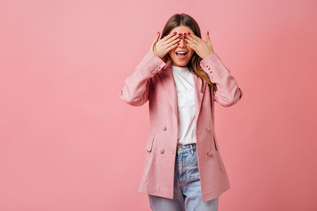 夹克有趣的女孩穿着休闲夹克遮住眼睛摄影棚拍摄的粉红色背景上的时尚女士情感微笑欢呼