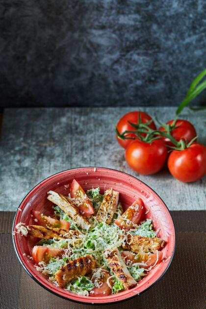 一餐一个红色的盘子 上面放着凯撒沙拉和西红柿健康奶酪菜