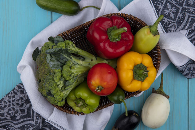 毛巾在蓝绿色背景下 厨房毛巾上的篮子里放着西红柿 黄瓜 甜椒和花椰菜花椰菜食物篮子