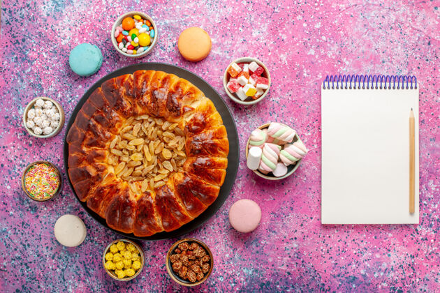 糖果顶视图五颜六色的法国马卡龙小美味蛋糕糖果和记事本上粉红色的桌子糖烤饼干饼干蛋糕派糖蔬菜视图