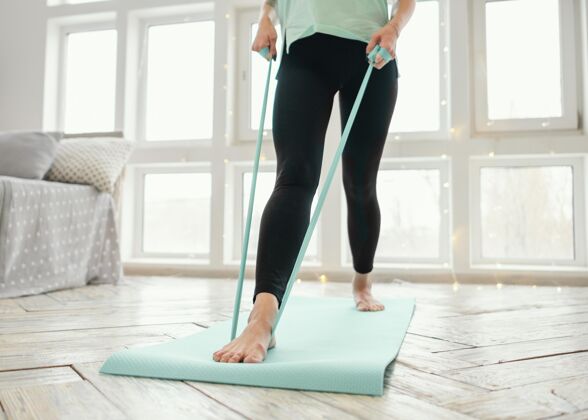 女人女性用橡皮筋在垫子上锻炼房子室内运动