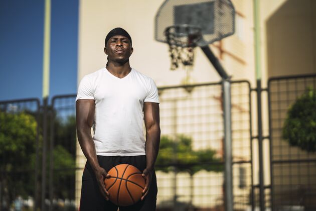 训练一个穿着白衬衫的非洲裔美国男子站在篮球场上的浅焦点运动装身体平衡
