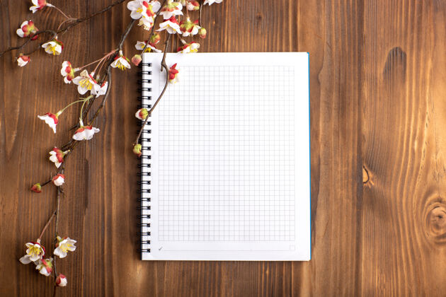 书桌顶视图打开文案与花在棕色的书桌上年份笔记本请柬